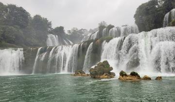 Wide cascading waterfalls with mist over rocks.