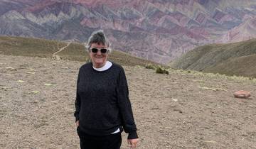 Person standing in front of colorful layered mountains, likely in Purmamarca.