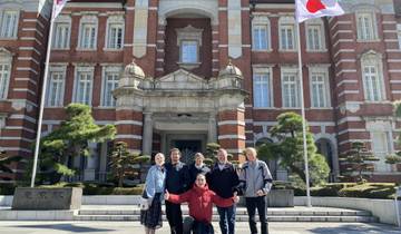 People posing in front of a historic building with Japanese flags.