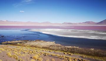 Vast desert landscape with a salt flat and distant mountains.