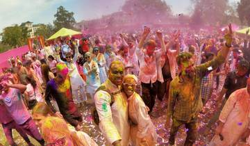 Large group celebrating Holi with vibrant colors and joyful expressions.