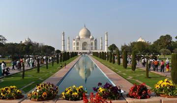 Taj Mahal with reflective pool and gardens filled with people.