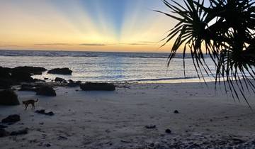 A serene sunset on a sandy beach with the silhouette of an island.