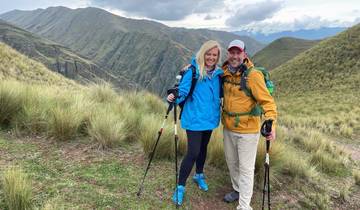 Couple posing on a scenic mountain trail with trekking poles.
