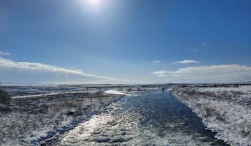 Snowy landscape with a clear river under a bright sun.