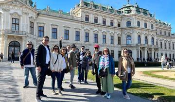 A group of people posing in front of an elegant baroque building.