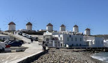 Row of traditional windmills by the sea with tourists.