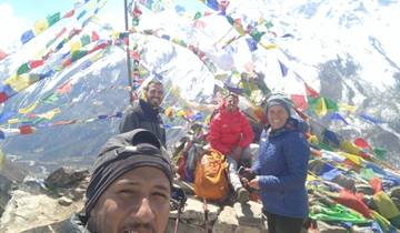 Group of people with prayer flags in a mountainous region.