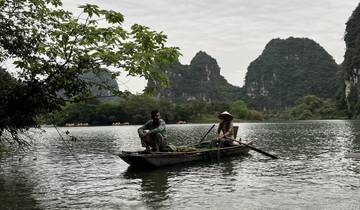Two people in a traditional boat on a peaceful river.