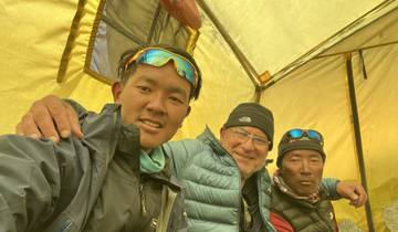 Three people sitting inside a tent.