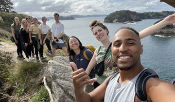 A group of people posing on a cliff with a scenic ocean view.