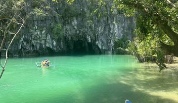 A small boat approaching a cave entrance surrounded by green water.