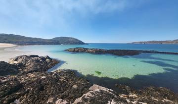 Panoramic view of a pristine beach with clear blue water and rocks