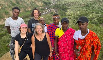 Group with Maasai individuals in traditional clothing on a hill.