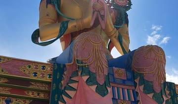 Large golden statue of a deity with mountain backdrop.