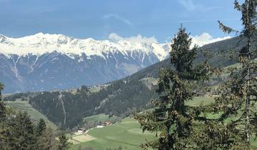 Mountain landscape with snowy peaks and green valleys.