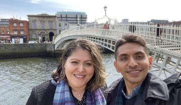 Two people taking a selfie on a bridge over a river.
