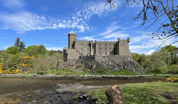 A large, historic castle situated on a rocky hilltop surrounded by greenery.