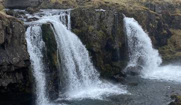 A small, tiered waterfall surrounded by rocky cliffs.