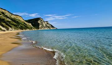 Pristine beach with cliffs and clear water under a blue sky.