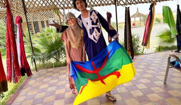 Two people holding a colorful flag in traditional dress.