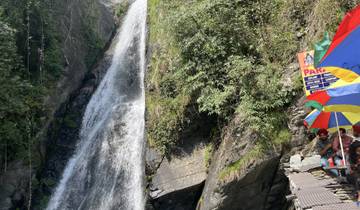 Group of people near a waterfall with umbrellas.