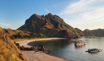 Secluded beach with hills and boats.