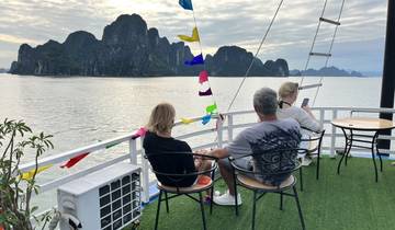 Three people enjoying a scenic view from a boat with rocky formations.