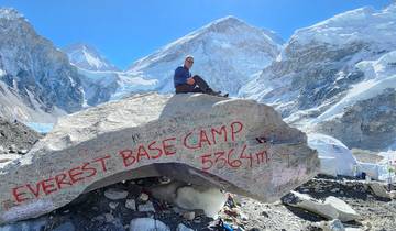 Man sitting on a rock at Everest Base Camp with mountains around.