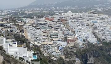 View of a Greek island town with white buildings on a hillside.