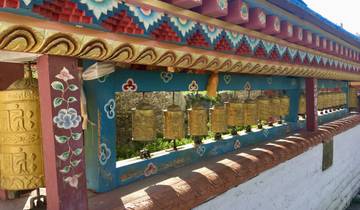 Decorative prayer wheels under an ornately painted structure.