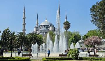 People enjoying a park with a mosque in the background.