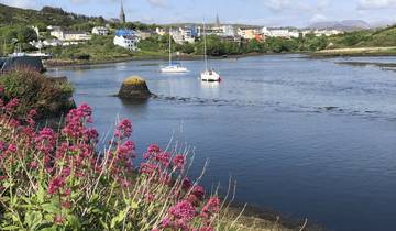 A picturesque bay with sailboats and colorful flowers in the foreground.