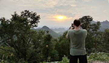 Person capturing a sunset over mountainous terrain.