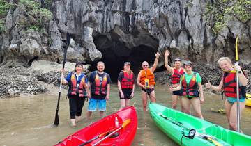 Group of people kayaking in front of a cave.