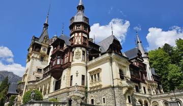 Peleș Castle with rich architectural details under a blue sky.