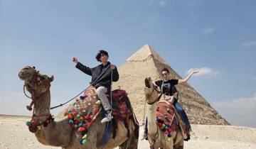Tourists on camels in front of a pyramid.