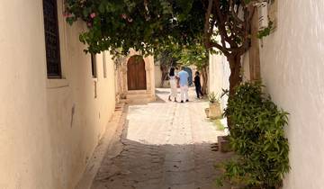 A charming narrow alleyway with people walking under a vine-covered arch.