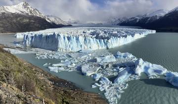 Large glacier with jagged ice and mountains in the background.