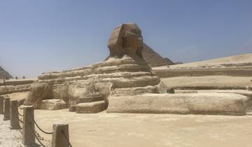 Statue of a sphinx with pyramids in the background.