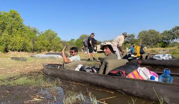People in small boats on a calm water body in a natural setting.