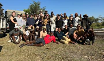 A large group of people posing together outdoors in a natural setting.