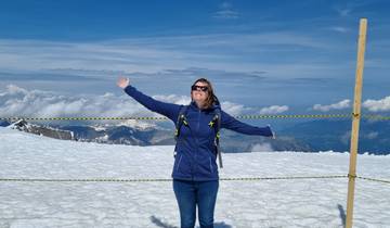 Person standing with arms wide open on a snowy mountain.