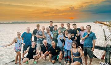 Large group of people enjoying a sunset by a river.