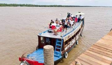 People gathered on a large riverboat near a dock.