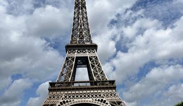 The Eiffel Tower in Paris against a cloudy blue sky.