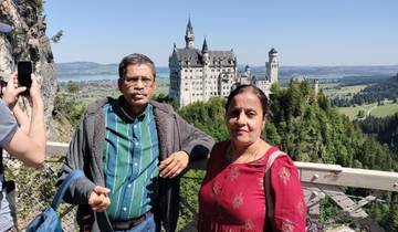 Two people posing in front of Neuschwanstein Castle.