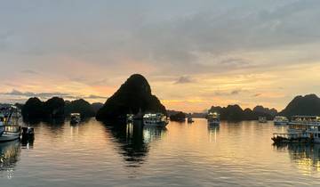 Boats floating among limestone karsts at sunset.