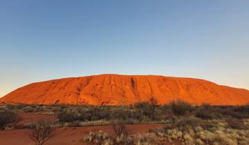 Uluru at dusk with a clear sky.
