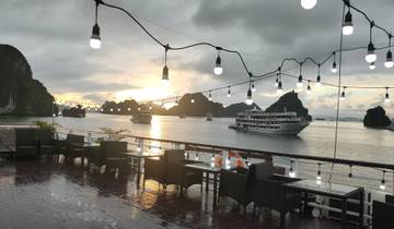 Dining area on a cruise ship with a sunset view of Halong Bay.